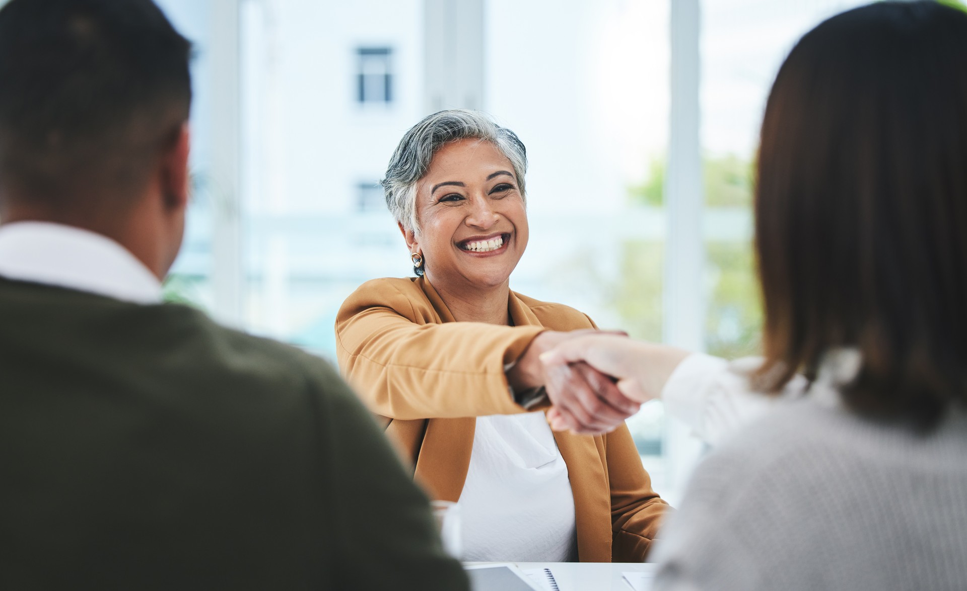 Apretón de manos, entrevista de trabajo o gente de negocios con una mujer madura feliz para la asociación en el cargo. Estamos contratando, sonriendo o gente de negocios dándose la mano para el éxito, la promoción o la negociación en la reunión